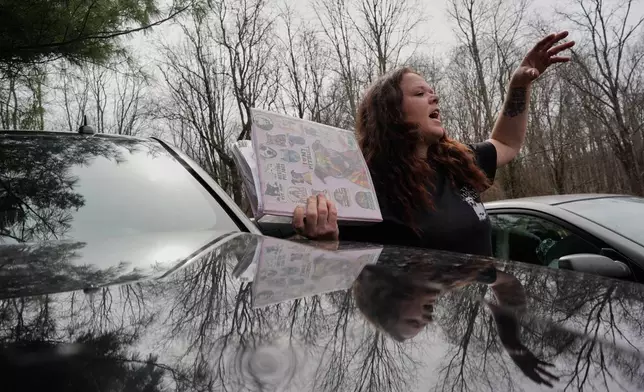 Ashley Nicole Dixon, clutching a binder with the records of pit bulls she has rescued, talks about her rising electric bills outside her home in Danese, W.Va., Saturday, March 21, 2026. (AP Photo/Carolyn Kaster)