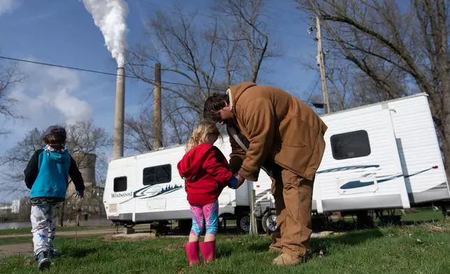 John White Jr. helps his daughter, Paisley, 3, zip her hoodie as his son, Malachi, 5, walks outside their home at the Lock 24 RV Park and Campground in Racine, Ohio, Saturday, March 14, 2026, across the Ohio River from the coal-fired Mountaineer Power Plant, near New Haven, W.Va. “In a winter season, I can say I pay a lot and honestly do not know how I do it. It has been hard,” said White Jr. who struggles to pay his utility bills. (AP Photo/Carolyn Kaster)