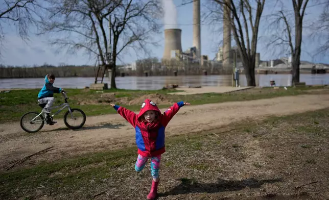 John White Jr.'s children, Paisley, 3, right, and Malachi, 5, play outside their home at the Lock 24 RV Park and Campground in Racine, Ohio, Saturday, March 14, 2026, across the Ohio River from the coal-fired Mountaineer Power Plant, near New Haven, W.Va. (AP Photo/Carolyn Kaster)