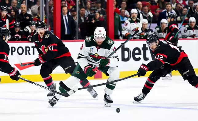Minnesota Wild's Yakov Trenin (13) chases down the puck as Ottawa Senators' Shane Pinto (12) works to prevent a play during the first period of an NHL hockey game, Saturday, April 4, 2026, in Ottawa, Ontario. (Spencer Colby/The Canadian Press via AP)