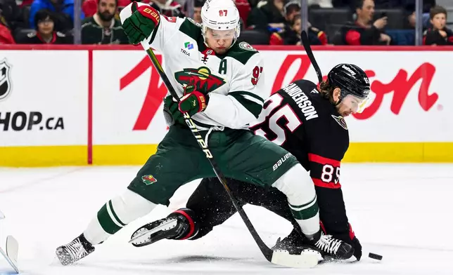 Minnesota Wild's Kirill Kaprizov (97) fights to maintain his balance as Ottawa Senators' Jake Sanderson (85) falls to the ice while chasing the puck during the first period of an NHL hockey game, Saturday, April 4, 2026, in Ottawa, Ontario. (Spencer Colby/The Canadian Press via AP)