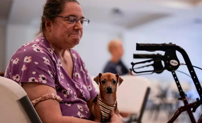 Jennifer Murphy and her dog Chip sit inside the Southside Baptist church as she is displanced by the Brantley Highway 82 fire, Friday, April 24, 2026, in Nahunta, Ga. (AP Photo/Mike Stewart)