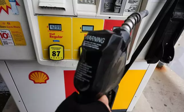 FILE - A gas price is displayed as a customer holds a fuel pump nozzle before filling up her vehicle's gas tank at a gas station, in Lincolnshire, Ill., Wednesday, April 15, 2026. (AP Photo/Nam Y. Huh, file)