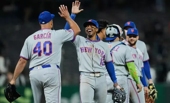 New York Mets shortstop Francisco Lindor (12) and pitcher Luis García (40) celebrate after the team's victory over the San Francisco Giants in a baseball game Friday, April 3, 2026, in San Francisco. (AP Photo/Godofredo A. Vásquez)