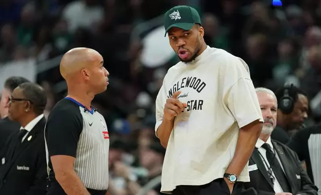 Injured Milwaukee Bucks' Giannis Antetokounmpo, center right, talks with an official, center left, during the first half of an NBA basketball game against the Boston Celtics, Friday, April 3, 2026, in Milwaukee. (AP Photo/Aaron Gash)