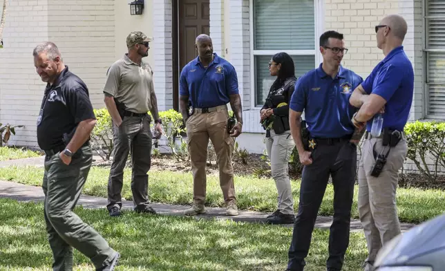 Detectives with the Hillsborough County Sheriff's Office join an investigation inside the Lake Forest subdivision of Tampa, Fla., on Friday, April 24, 2026, where authorities said a man was taken into custody after barricading himself inside a home, in connection to the search for two missing University of South Florida graduate students. (Douglas R. Clifford/Tampa Bay Times via AP)