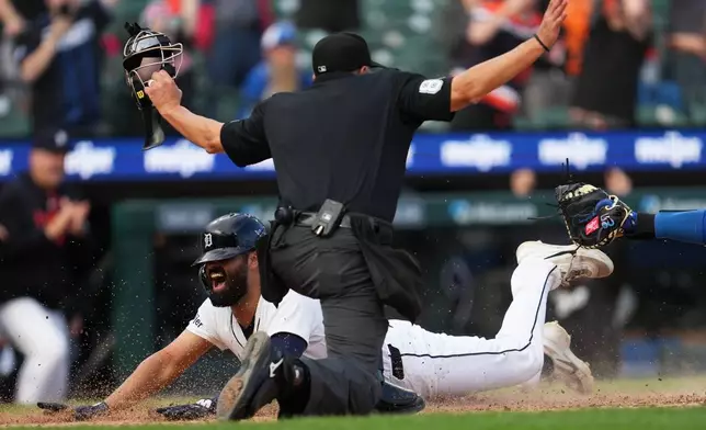 Detroit Tigers' Riley Greene slides safely into home plate past the tag of Kansas City Royals catcher Carter Jensen during the ninth inning of a baseball game Thursday, April 16, 2026, in Detroit. (AP Photo/Paul Sancya)