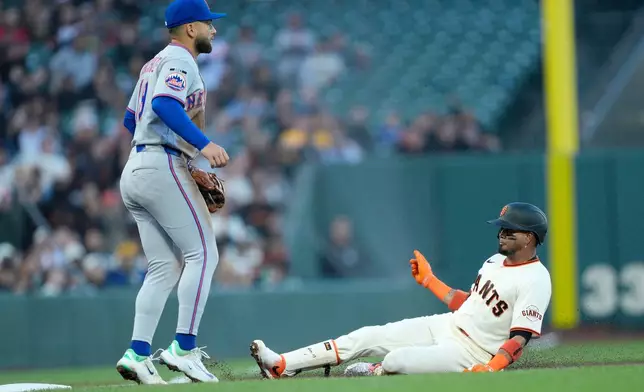 San Francisco Giants' Luis Arraez slides into third base in front of New York Mets third baseman Bo Bichette, left, after hitting a RBI triple during the first inning of a baseball game in San Francisco, Thursday, April 2, 2026. (AP Photo/Tony Avelar)