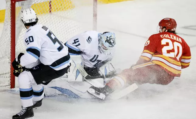 Utah Mammoth goalie Vitek Vanecek, center, lets in a goal from Calgary Flames' Blake Coleman, right, as Sean Durzi looks on during the third period of an NHL hockey game in Calgary on Sunday, April 12, 2026. (Jeff McIntosh/The Canadian Press via AP)