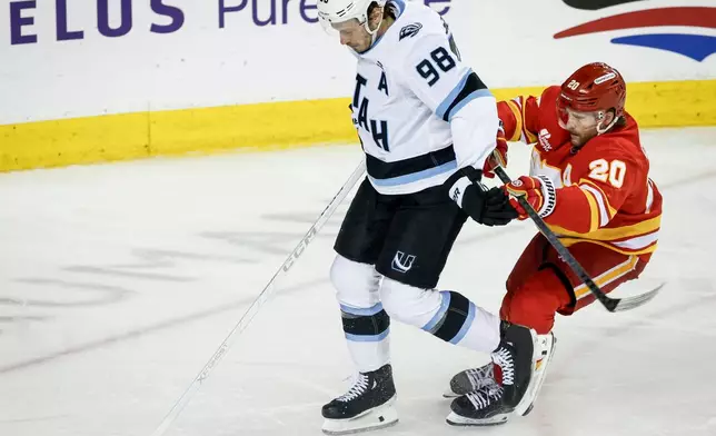 Utah Mammoth's Mikhail Sergachev, left, is checked by Calgary Flames' Blake Coleman during the third period of an NHL hockey game in Calgary on Sunday, April 12, 2026. (Jeff McIntosh/The Canadian Press via AP)