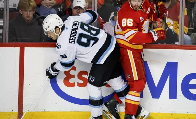 Utah Mammoth's Mikhail Sergachev, left, checks Calgary Flames' Joel Farabee during the third period of an NHL hockey game in Calgary on Sunday, April 12, 2026. (Jeff McIntosh/The Canadian Press via AP)
