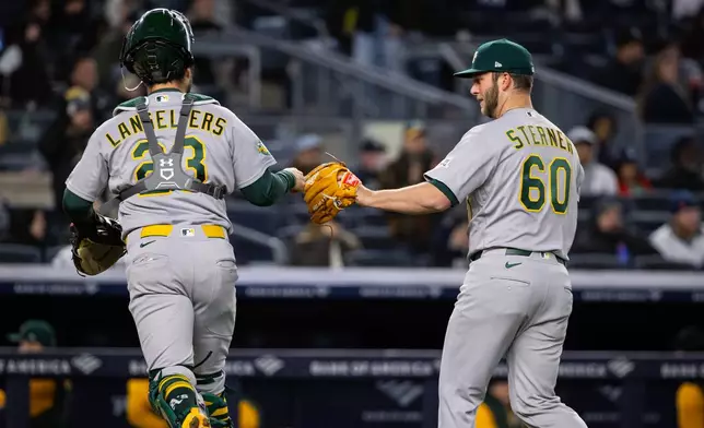 Athletics catcher Shea Langeliers (23) and Athletics pitcher Justin Sterner (60) bump fists during the sixth inning of a baseball game against the New York Yankees, Tuesday, April 7, 2026, in New York. (AP Photo/Angelina Katsanis)