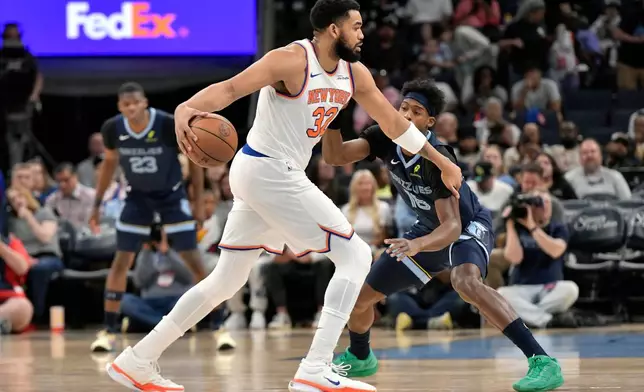 New York Knicks center Karl-Anthony Towns (32) handles the ball against Memphis Grizzlies forward Olivier-Maxence Prosper (18) in the first half of an NBA basketball game Wednesday, April 1, 2026, in Memphis, Tenn. (AP Photo/Brandon Dill)