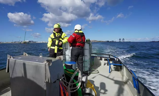 Archaeologists sail with boat through the harbor in Copenhagen, Denmark, Tuesday, March 31, 2026. (AP Photo/James Brooks)