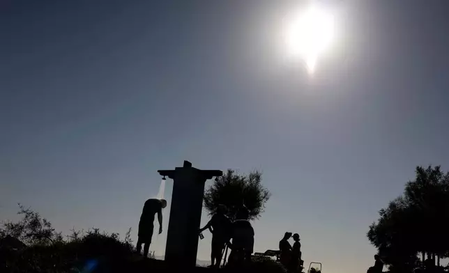 FILE - A man takes a shower near a beach during a hot day in Palaio Faliro suburb, south of Athens, Greece, July 6, 2025. (AP Photo/Yorgos Karahalis, File)