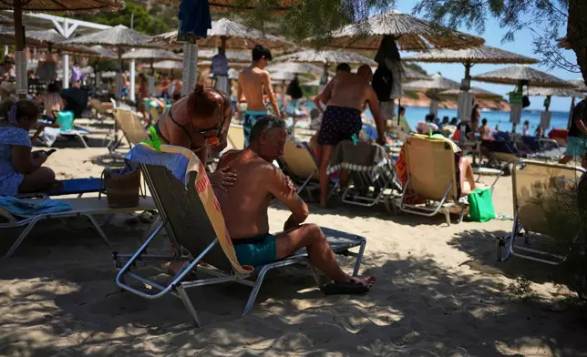 FILE - A woman applies sunscreen to a man at Avlaki beach east of Athens, Greece, Aug. 7, 2025. (AP Photo/Thanassis Stavrakis, File)