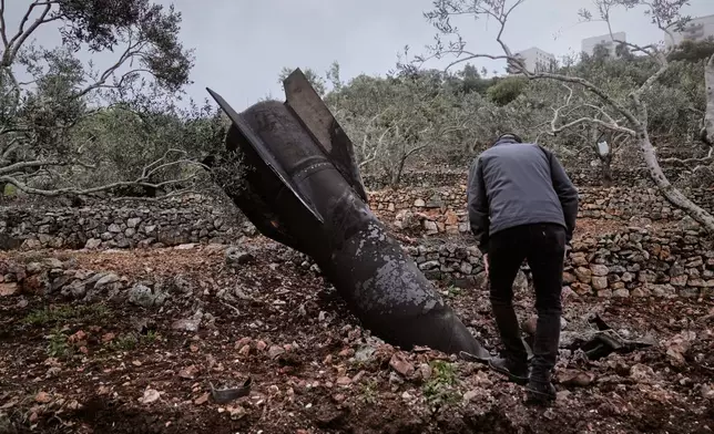 A man inspect the wreckage of an Iranian missile that landed near the West Bank village of Marda, Tuesday, March 31, 2026. (AP Photo/Majdi Mohammed)