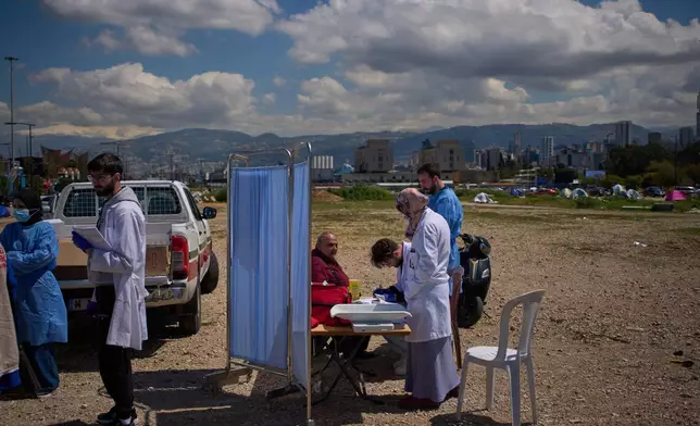 A displaced man receives medical care at a temporary mobile clinic set up near tents sheltering people who fled Israeli airstrikes, in Beirut, Lebanon, Tuesday, March 31, 2026. (AP Photo/Emilio Morenatti)