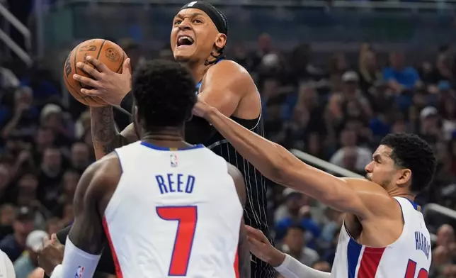 Orlando Magic forward Paolo Banchero, center, goes up for a shot over Detroit Pistons forward Paul Reed (7) and forward Tobias Harris, right, during the second half in Game 3 of a first-round NBA basketball playoff series, Saturday, April 25, 2026, in Orlando, Fla. (AP Photo/John Raoux)