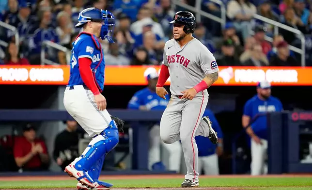 Boston Red Sox's Willson Contreras, right, scores on a single by teammate Marcelo Mayer as Toronto Blue Jays catcher Tyler Heineman, left, looks on during fourth-inning baseball game action in Toronto, Monday, April 27, 2026. (Frank Gunn/The Canadian Press via AP)