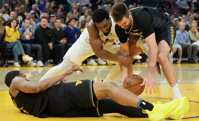 Cleveland Cavaliers guard Donovan Mitchell, middle, reaches for the ball against Golden State Warriors guard Pat Spencer, right, and guard De'Anthony Melton, bottom, during the first half of an NBA basketball game in San Francisco, Thursday, April 2, 2026. (AP Photo/Jeff Chiu)