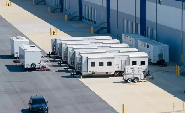 A security vehicle drives past trailers outside a proposed ICE detention center in a small community in western Maryland known as a destination for weekend bicyclists and Civil War history buffs in Williamsport, Md., Thursday, March 26, 2026. (AP Photo/Steve Helber)