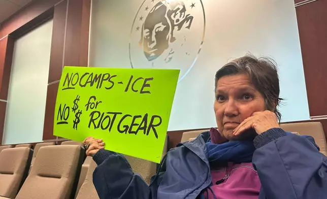 Carol Antoniewicz holds a sign against a planned immigration detention facility during a a Washington County Commission meeting in Hagerstown, Md., Tuesday, March 31, 2026. (AP Photo/Nathan Ellgren)