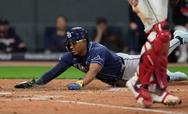 Tampa Bay Rays' Richie Palacios, left, scores behind Cleveland Guardians catcher Austin Hedges in the eighth inning of a baseball game in Cleveland, Monday, April 27, 2026. (AP Photo/Sue Ogrocki)