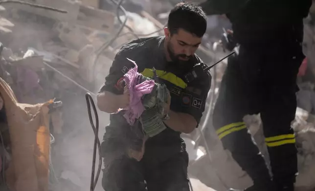 A rescue worker holds money recovered from the rubble of a destroyed building that was hit a day ahead in an Israeli airstrike in central Beirut, Lebanon, Thursday, April 9, 2026. (AP Photo/Hussein Malla)