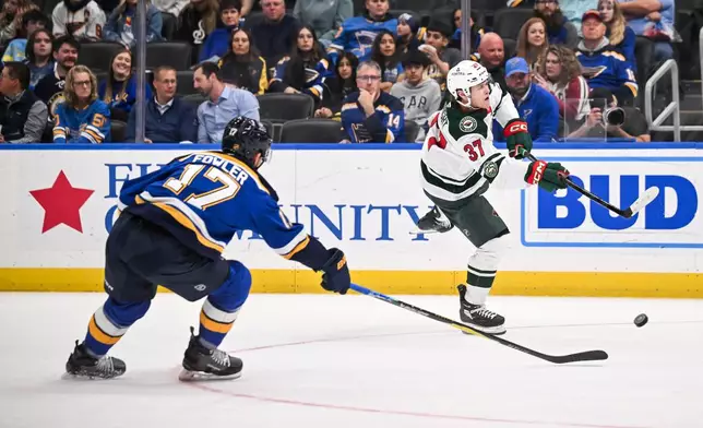 Minnesota Wild's Hunter Haight (37) shoots while St. Louis Blues' Cam Fowler (17) defends during the third period of an NHL hockey game Monday, April 13, 2026, in St. Louis. (AP Photo/Connor Hamilton)