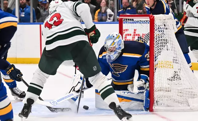 St. Louis Blues' Joel Hofer (30) defends the net against Minnesota Wild's Yakov Trenin (13) during the third period of an NHL hockey game Monday, April 13, 2026, in St. Louis. (AP Photo/Connor Hamilton)