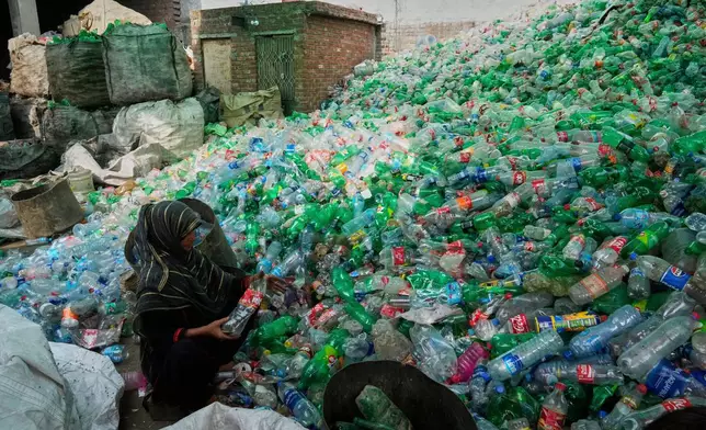 FILE - A worker sorts through empty bottles at a plastic recycling factory in Lahore, Pakistan, Aug. 7, 2025. (AP Photo/K.M. Chaudary, File)