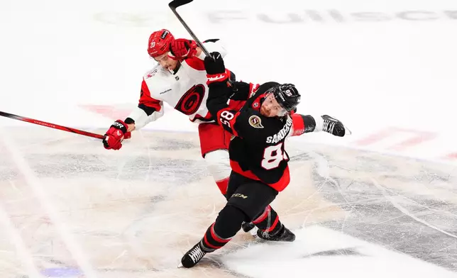 Carolina Hurricanes' Sebastian Aho (20) and Ottawa Senators' Jake Sanderson (85) collide during second period of an NHL playoff hockey game in Ottawa on Thursday, April 23, 2026. (Sean Kilpatrick/The Canadian Press via AP)