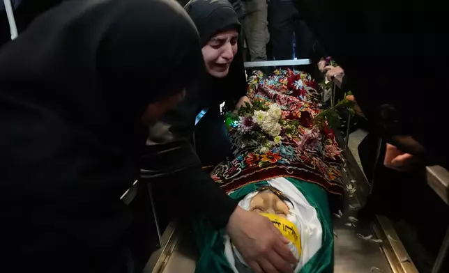 FILE — Malak Meslmani, center, the mother of Jawad Younes, 11, who was was killed in an Israeli airstrike, mourns over her son's body during his funeral procession in Saksakieh village, south Lebanon, Saturday, March 28, 2026. (AP Photo/Hussein Malla, File)