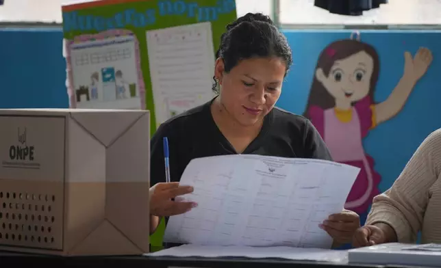 An election official checks voter lists as voting resumes at polling stations affected by delays and logistical problems during general elections in Lima, Peru, Monday, April 13, 2026. (AP Photo/Guadalupe Pardo)