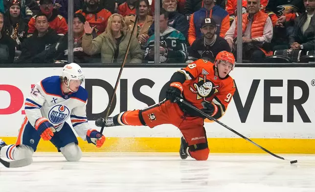 Anaheim Ducks defenseman Pavel Mintyukov, right, falls as he passes the puck while under pressure from Edmonton Oilers right wing Kasperi Kapanen during the first period of Game 3 in the first round of the NHL hockey Stanley Cup playoffs Friday, April 24, 2026, in Anaheim, Calif. (AP Photo/Mark J. Terrill)