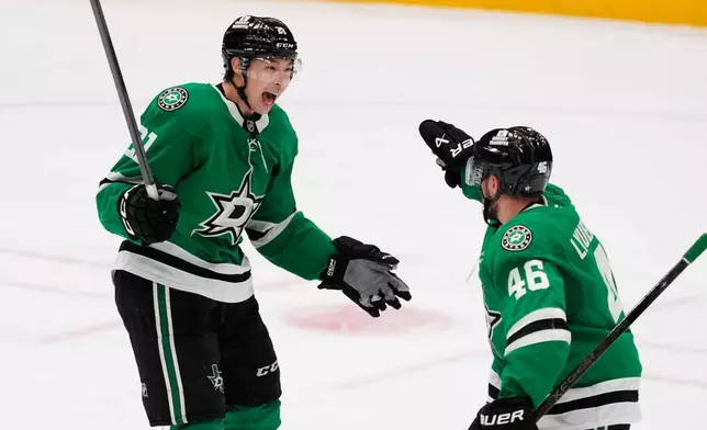 Dallas Stars left wing Jason Robertson (21) and Ilya Lyubushkin (46) celebrate after Robertson scored in the third period of an NHL hockey game against the Minnesota Wild Thursday, April 9, 2026, in Arlington, Texas. (AP Photo/Tony Gutierrez)