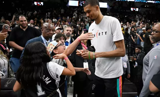 San Antonio Spurs center Victor Wembanyama, center right, greets fans after an NBA basketball game against the Dallas Mavericks, Friday, April 10, 2026, in San Antonio. (AP Photo/Darren Abate)