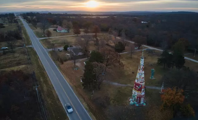 The sun rises over the horizon as a vehicle travels near a large Totem Pole at Ed Galloway's Totem Pole Park in Chelsea, Okla., Wednesday, Nov. 19, 2025. (AP Photo/Julio Cortez)