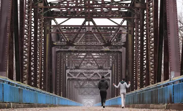Reygan Calloway, right, and her boyfriend Jordan Smith walk across the Old Chain of Rocks Bridge spanning the Mississippi River from Illinois to Missouri and is now part of the Route 66 Bikeway in Madison, Ill., Thursday, Nov. 20, 2025. (AP Photo/Jeff Roberson)