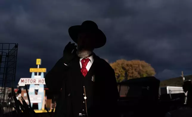 Jeff Smith, a part-time employee at a souvenir shop, smokes a cigar as a shaft of sunlight illuminates him in Williams, Ariz., a town on historic Route 66, Thursday, Nov. 20, 2025. (AP Photo/Jae C. Hong)