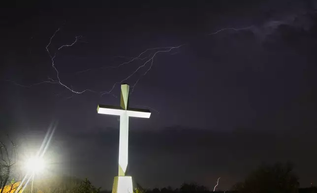 Lightning is visible on the sky near a large cross at the grounds of Life.Church, where Route 66 meets with Interstate-35 in Edmond, Okla, Wednesday, Nov. 19, 2025. (AP Photo/Julio Cortez)