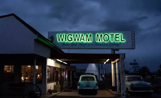 Vintage cars sit beneath a neon sign at the Wigwam Motel, a landmark along historic Route 66, in Holbrook, Ariz., Wednesday, Nov. 19, 2025. (AP Photo/Jae C. Hong)