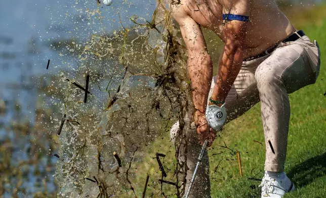 FILE - Michael Brennan sends mud and water flying as he tries to hit his ball out of floating debris on the 18th hole, only to have it land back in the water, during the first round of the PGA Zurich Classic golf tournament at TPC Louisiana, in Avondale, April 23, 2026. (AP Photo/Matthew Hinton, File)