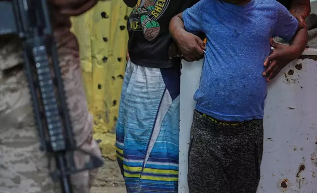 FILE - Children stand next to a police officer during a visit from Jordanian Princess Sarah Zeid, a World Food Programme advisor, at a shelter for families displaced by gang violence, in Port-au-Prince, Haiti, April 27, 2026. (AP Photo/Odelyn Joseph, File)