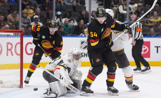 Vegas Golden Knights goalie Carter Hart (79) makes a save as Vancouver Canucks' Aatu Raty (54) watches the puck go wide of the net during the third period of an NHL hockey game, in Vancouver, British Columbia, Tuesday, April 7, 2026. (Darryl Dyck/The Canadian Press via AP)