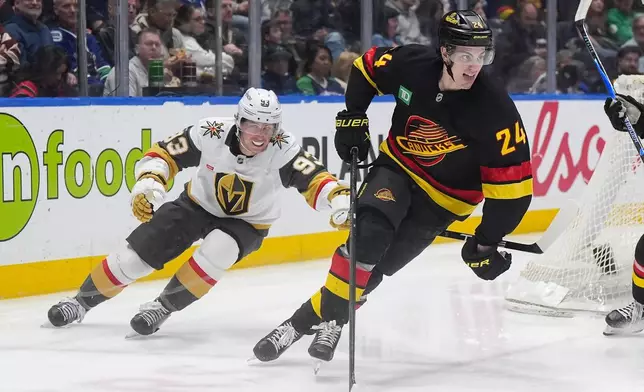 Vancouver Canucks' Zeev Buium (24) skates with the puck away from Vegas Golden Knights' Mitch Marner (93) during the second period of an NHL hockey game, in Vancouver, on Tuesday, April 7, 2026. (Darryl Dyck/The Canadian Press via AP)
