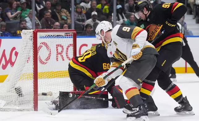Vegas Golden Knights' Jack Eichel (9) puts a shot wide of the net behind Vancouver Canucks goalie Nikita Tolopilo (60) while being checked by Victor Mancini (90) during the second period of an NHL hockey game, in Vancouver, on Tuesday, April 7, 2026. (Darryl Dyck/The Canadian Press via AP)