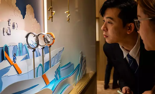 Visitors look at watches at the Swiss watch manufacturer Vacheron Constantin stand, during the opening day of the "Watches and Wonders Geneva" luxury watch fair, in Geneva, Switzerland, Tuesday, April 14, 2026. (Salvatore Di Nolfi/Keystone via AP)