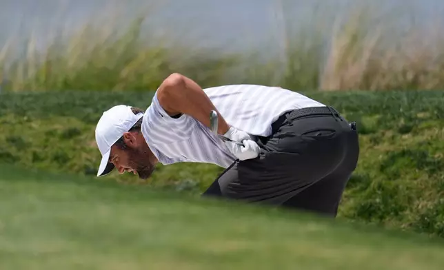 Scottie Scheffler inspects his ball in a bunker on the 18th hole during the second round at the RBC Heritage golf tournament Friday, April 17, 2026, in Hilton Head, S.C. (AP Photo/Mike Stewart)